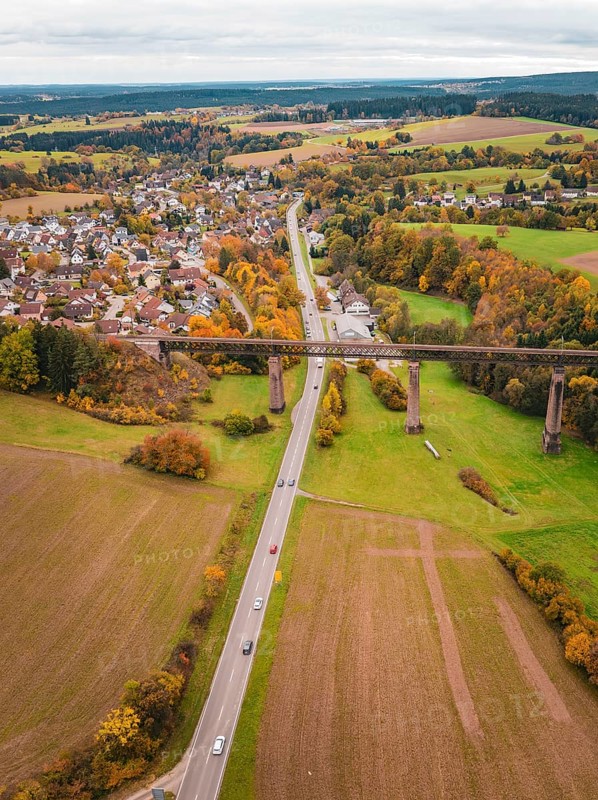 River and road criss-cross autumnal landscape with bridge and nearby village, Dornstetten, Freudenstadt district, Germany