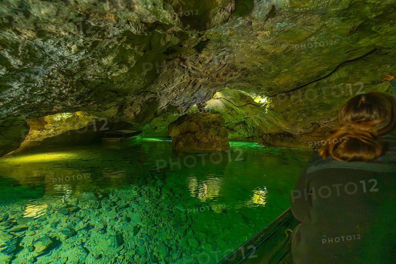 Interior of a cave with green water and rocks, people exploring the underground body of water, Wimsener Höhle, Hayingen, Germany