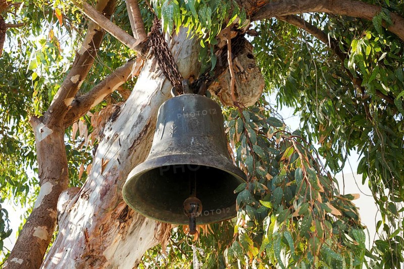 Church bell hangs in a tree in Chora, old town of Naxos, Naxos, Cyclades, Greece