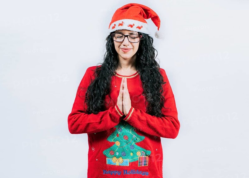 Hopeful Young woman in Christmas sweater making a wish, isolated. Hopeful girl in Christmas hat making a wish isolated