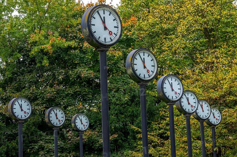 The art installation Zeitfeld in Volksgarten Park in Düsseldorf-Oberbilk, a total of 24 station clocks, on 6 meter high steel columns, have been running synchronously since 1987, dial shows five to twelve, artwork by Düsseldorf artist Klaus Rinke, symbol of time, time change, North Rhine-Westphalia, Germany