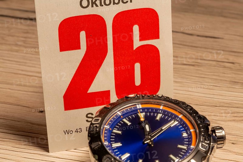 Wintertime 2025 time change: Close-up of a wristwatch and a sheet of a tear-off calendar showing the date October 26