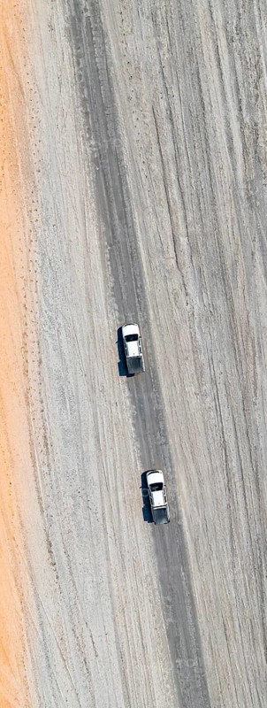 Aerial view, top-down view, two off-road cars driving on a road in arid countryside, Botswana