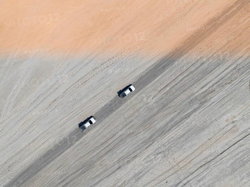 Aerial view, top-down view, two off-road cars driving on a road in arid countryside, Botswana