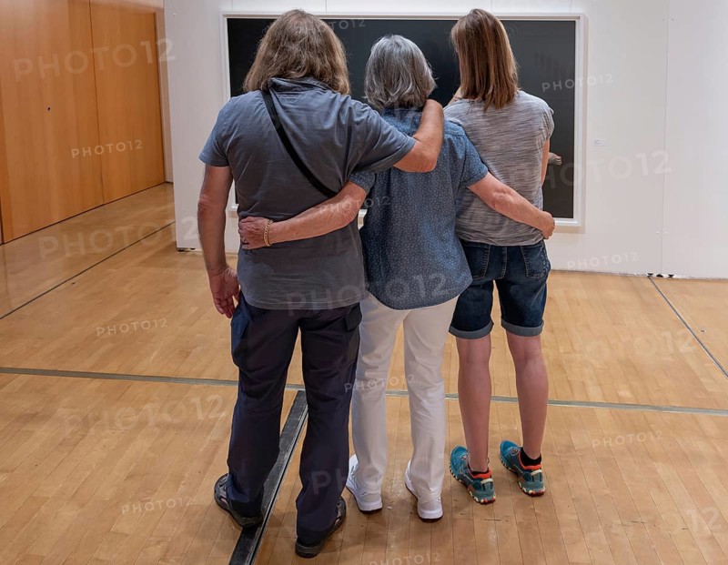 Three visitors look at a painting in an exhibition, Bavaria, Germany
