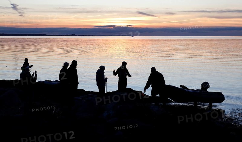 Angler on the beach during sunset, an angler docks on the shore with his inflatable boat, Fehmarn island, 18.10.2025, Fehmarn, Schleswig-Holstein, Germany