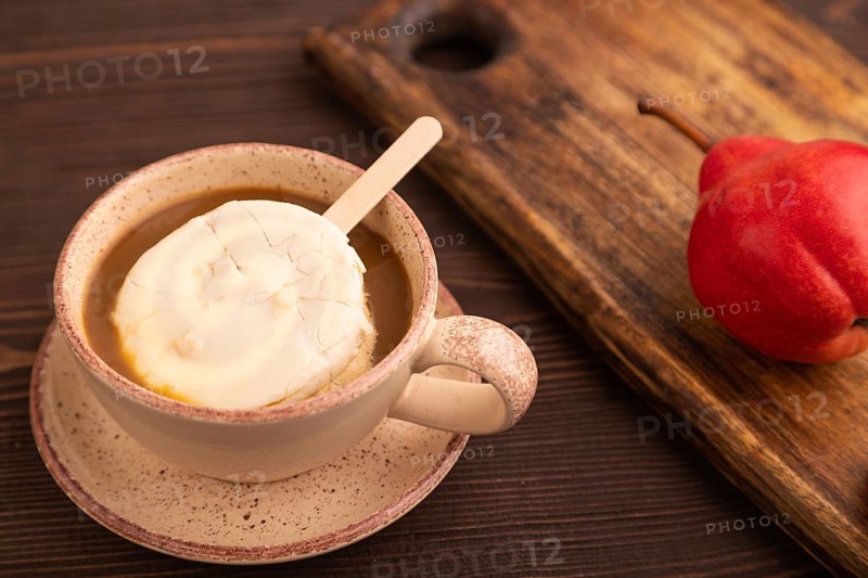 ?hocolate Ice cream in white glaze, cup of coffee, on brown wooden background, side view, close up, selective focus