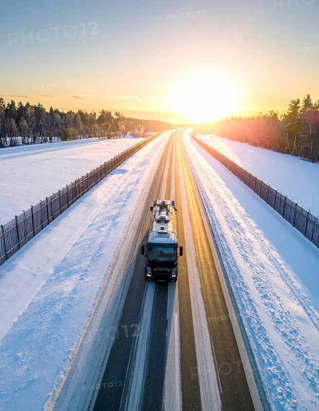 Petrol cargo truck lorry tanker driving on highway hauling oil products at sunrise, wide snowy landscape in winter, AI generated