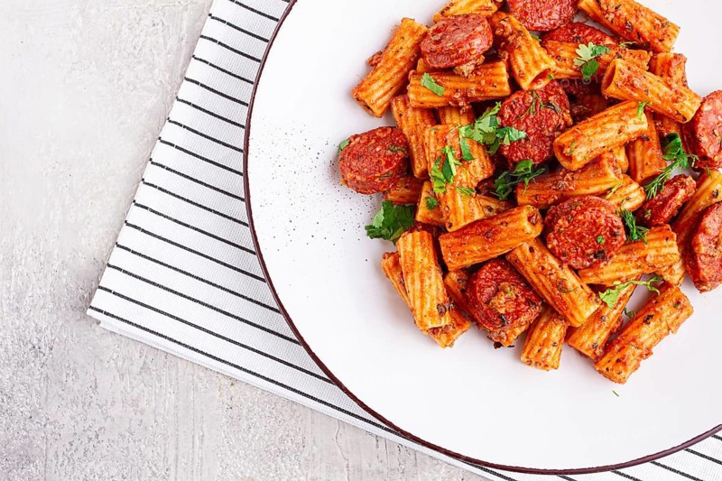 Rigatoni pasta with spicy sausage, and rich tomato sauce served, on a white plate, homemade