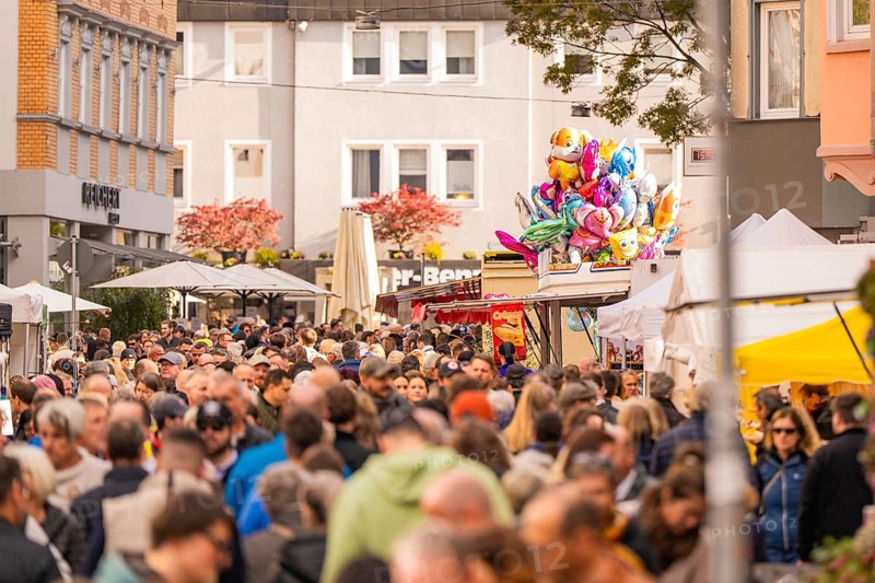 Busy shopping street in autumn, people strolling between modern buildings and colorful shops, Urschelherbst street festival, Nagold, Germany