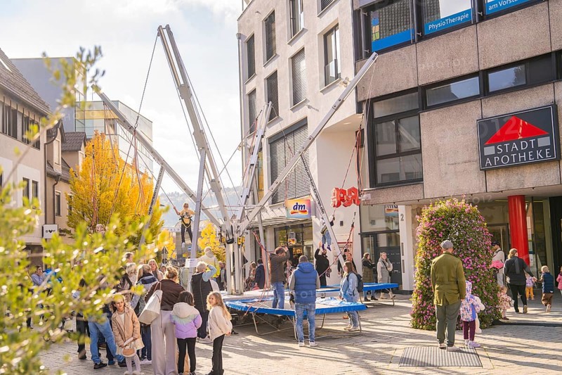 People enjoy activities on bungee trampolines in front of municipal shops and a pharmacy, Urschelherbst Street Festival, Nagold, Germany