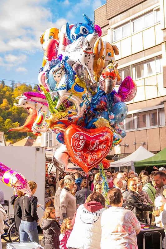 Various colorful balloons, including a heart with 'I Love You, 'float above a celebratory crowd, Urschelherbst street festival, Nagold, Germany