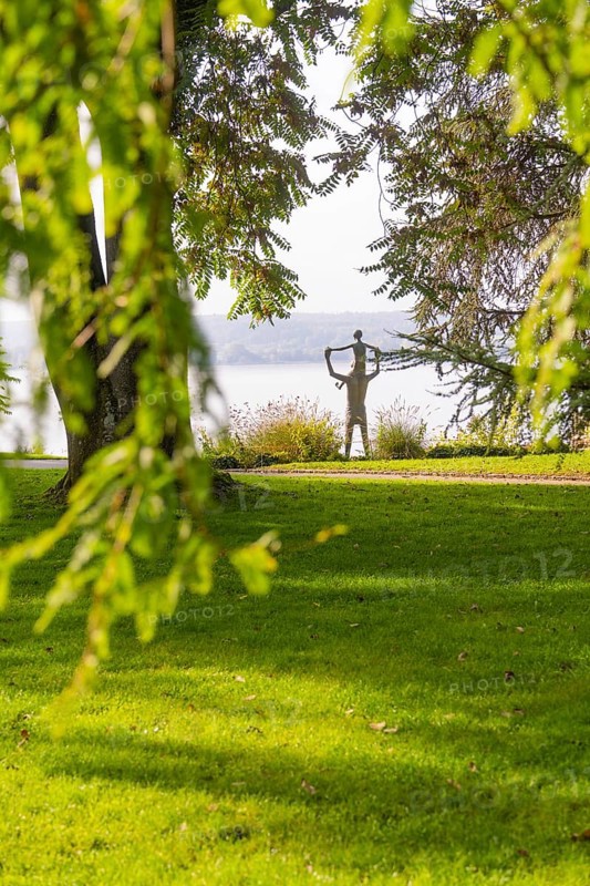 Parkland with a sculpture and view of the lake, surrounded by lush nature, Überlingen, Lake Constance, Germany