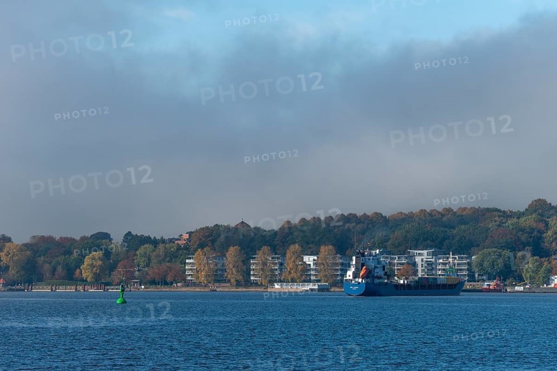 Kiel Fjord, Holtenau district, Kiel, modern apartments on the river bank, cargo ship, hillside, forest, Baltic Sea, Schleswig-Holstein, Germany