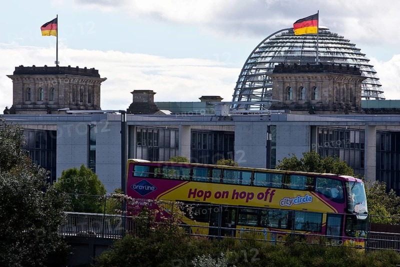 Reichstag dome with German flags and double-decker bus of the city tour hop on hpo off, German Bundestag, government district, Berlin, Germany