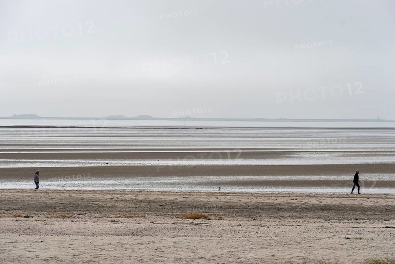 Two people walking on the wide beach of the island of Föhr, Schleswig-Holstein, Germany, at low tide