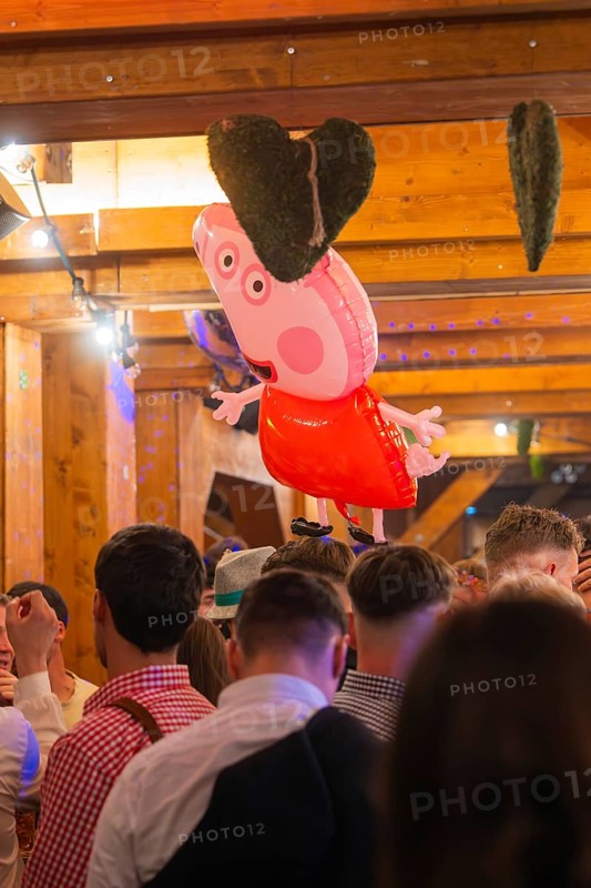A pink heart-shaped balloon floats above a crowd in a traditional wooden house, Cannstatter Wasen folk festival, Sonja Merz marquee, Stuttgart, Germany