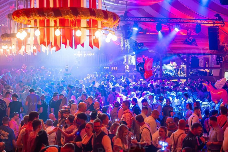 A lively party in a festive beer tent with stage and illuminated atmosphere at night, Volksfest Cannstatter Wasen, Sonja Merz Festzelt, Stuttgart, Germany