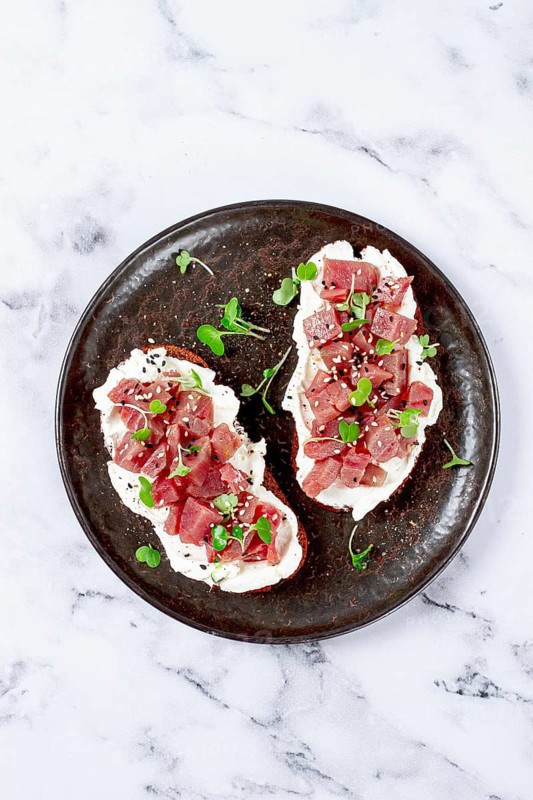 Sandwiches, rye bread with cream cheese, sliced tuna fillet with herbs, breakfast on a black plate, homemade