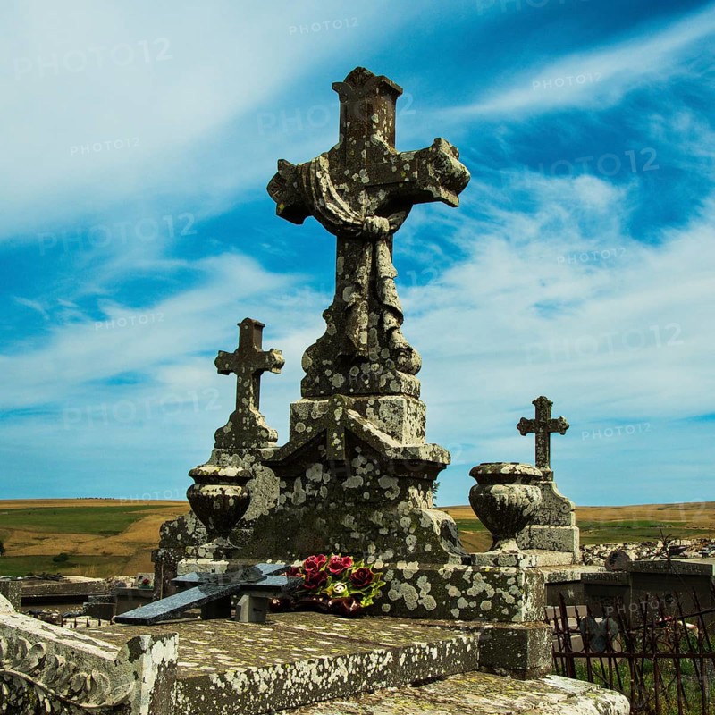 Crosses stand tall against a colorful sunset sky, showcasing the beauty of an ancient cemetery. Cantal. Auvergne Rhone Alpes. France