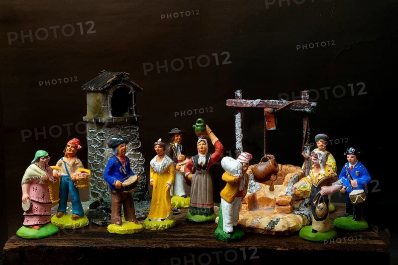 Colorful Provençal terracotta Santons figurines showcase characters engaged in various activities, featuring artisans, farmers, and market sellers in a quaint village setting