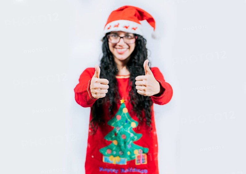 Young woman in Christmas sweater gesturing Ok with thumbs up. isolated. Smiling girl in Christmas sweater giving thumbs up