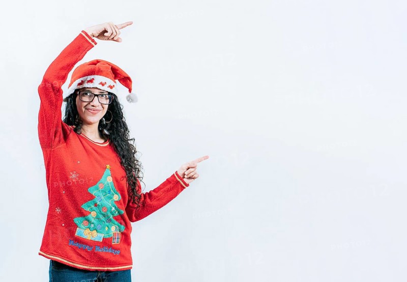 Happy young woman in Christmas sweater recommending and pointing aside. Smiling girl in Christmas sweater pointing to the side, isolated