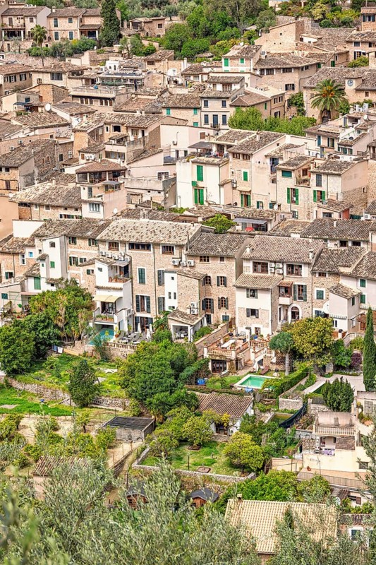 Aerial view at an old mountain village with residential houses and lush green gardens in the summer, Fornalutx, Mallorca, Spain