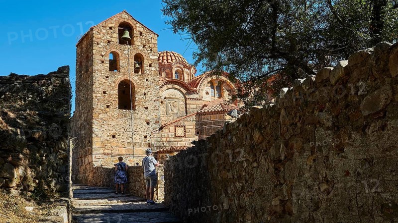 Metropolis, Metropolitan Church of Agios Dimitrios Mystras, Ornamented Byzantine church with trees and two people on a path, Mystras, Mistra, UNESCO World Heritage Site, Medieval Byzantine ruined city, northwest of Sparta, foothills of the Taygetos Mountains, Peloponnese, peninsula, Greece