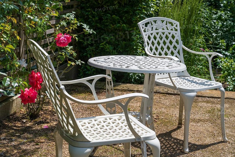 Sitting area in the garden, table and two garden chairs, framed by blooming roses, Westphalia, North Rhine-Westphalia, Germany