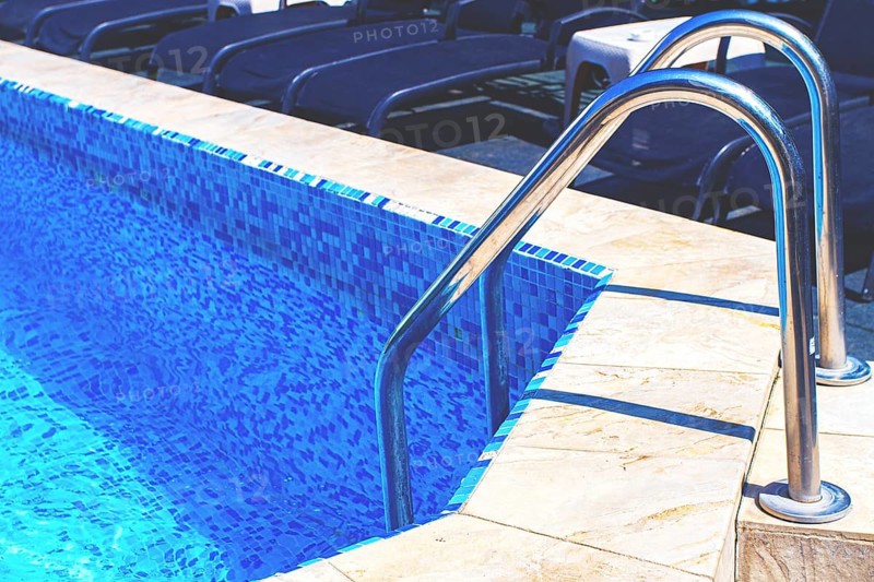 Bright blue swimming pool with ladder under clear sky, perfect for relaxation on a sunny day