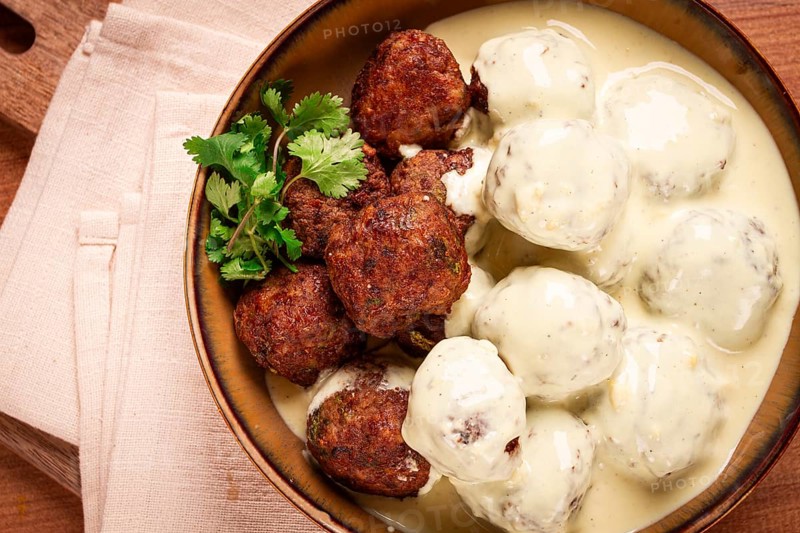 Swedish meatballs in cream sauce, plate on a wooden table, homemade, no people