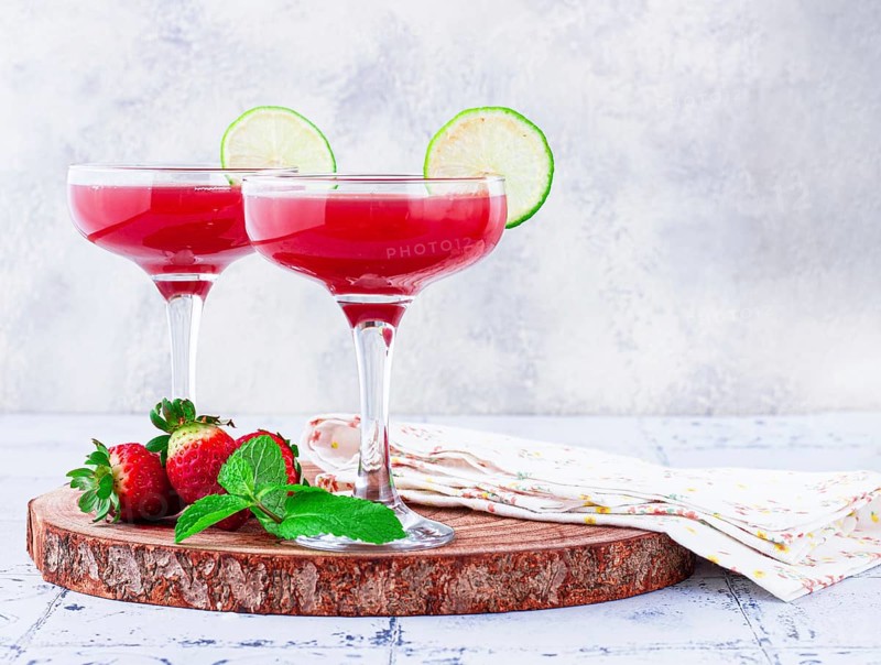 Refreshing cocktail in an elegant glass with lime and strawberries, sunshine, no people
