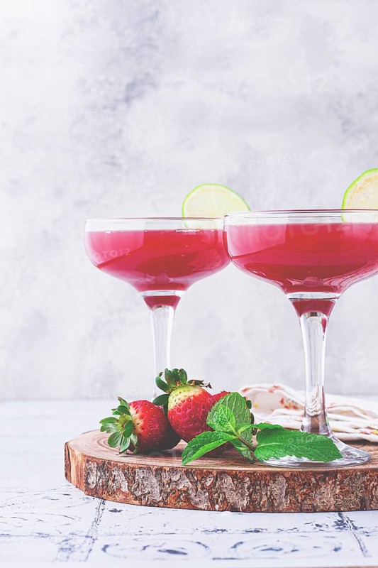 Refreshing cocktail in an elegant glass with lime and strawberries, sunshine, no people