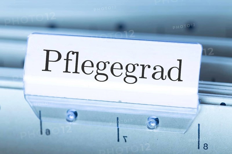 (Photomontage) Sign with the inscription PFLEGEGRAD on a suspension file folder