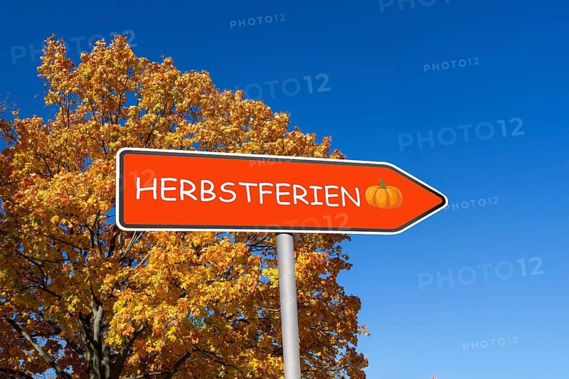 (Photomontage) Directional arrow with the inscription HERBSTFERIEN in front of an autumn-coloured tree