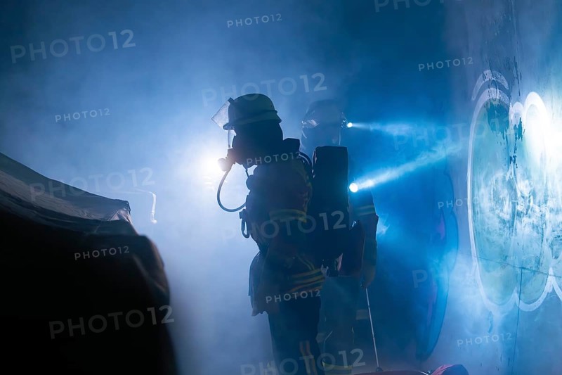 Firefighters in protective suits work in the fog, beams of light cut through the smoke, firefighting exercise in the new construction tunnel of the Hermann Hesse railway, Ostelsheim, district of Calw, Germany