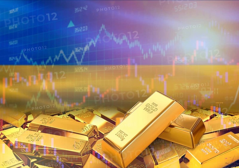 Gold bars on Ukraine flag in background. Gold bars stacked on Ukrainian flag. Concept of Ukraine gold reserves