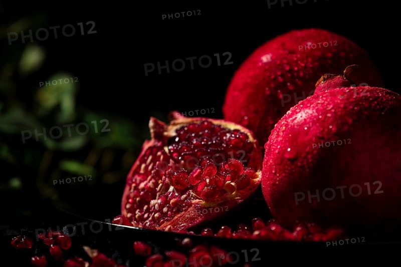 Sliced pomegranate with protruding seeds in a dark atmosphere