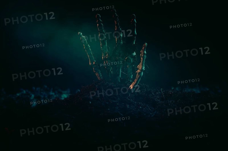 A single skeletonised hand protruding eerily from the dark earth, Halloween