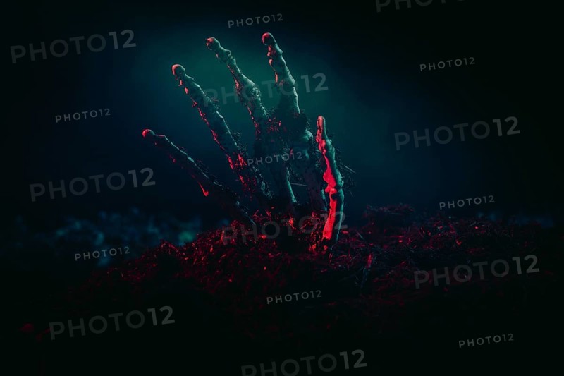A skeleton hand shining menacingly from the earth in the light, Halloween
