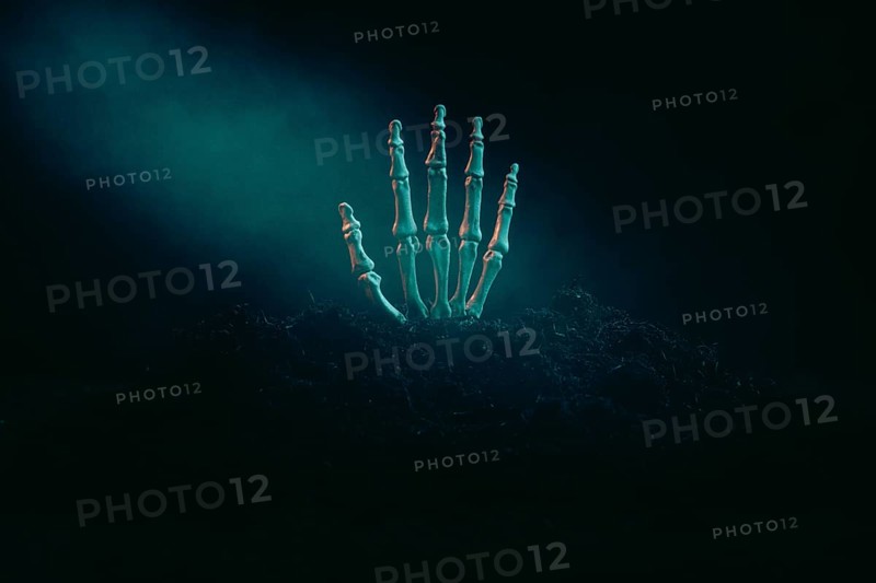 A skeleton hand protruding from the dark earth in the dim light, Halloween