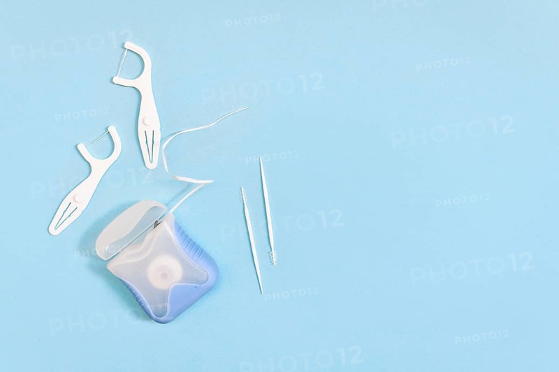 Dental floss and toothpicks on blue background with copy space. Oral hygiene products