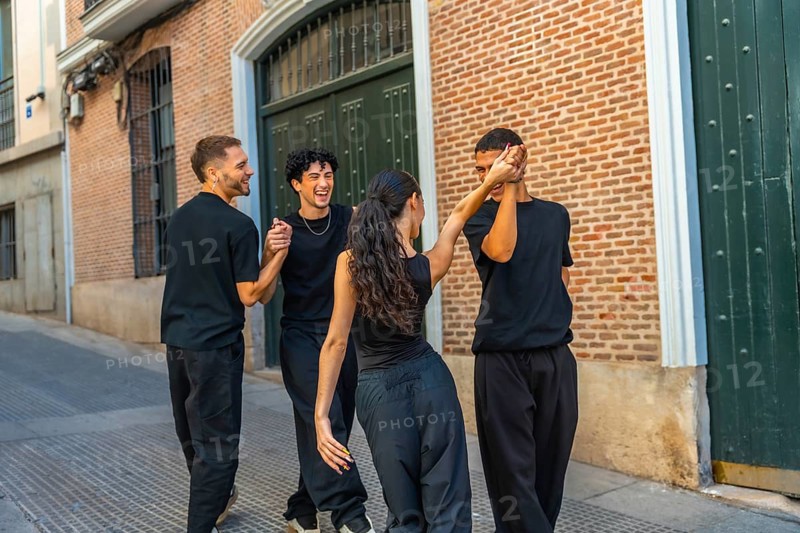 Young diverse friends dancing and laughing together on an urban street, holding hands and celebrating joyful, energetic friendship, freedom and community connection