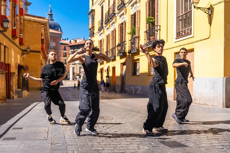 Four young dancers expressing themselves through contemporary dance, performing a street choreography on a sunny day in an old cobblestone street in madrid, spain