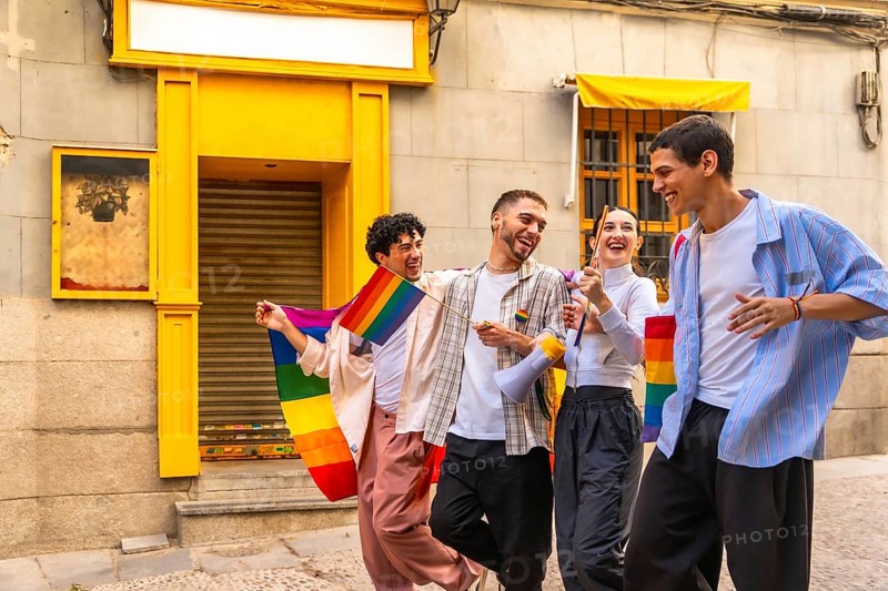 Young diverse friends celebrating lgbtqia plus pride, walking cheerfully on a city street, carrying rainbow flags and a megaphone, embracing joy and community