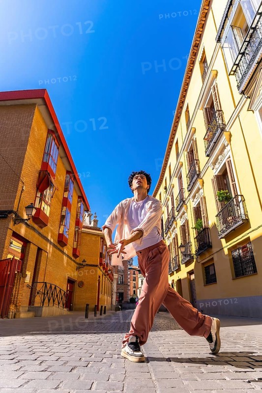Young man expressing movement and freedom through contemporary dance in an old european city street, creating an urban art scene under a clear blue sky