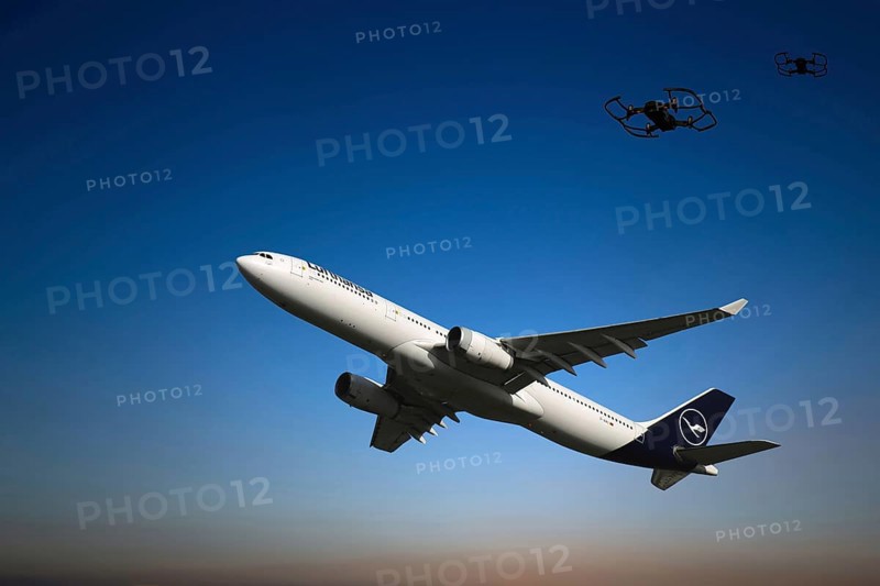 (Photomontage) Lufthansa aircraft taking off in the evening sky, two drones in the background