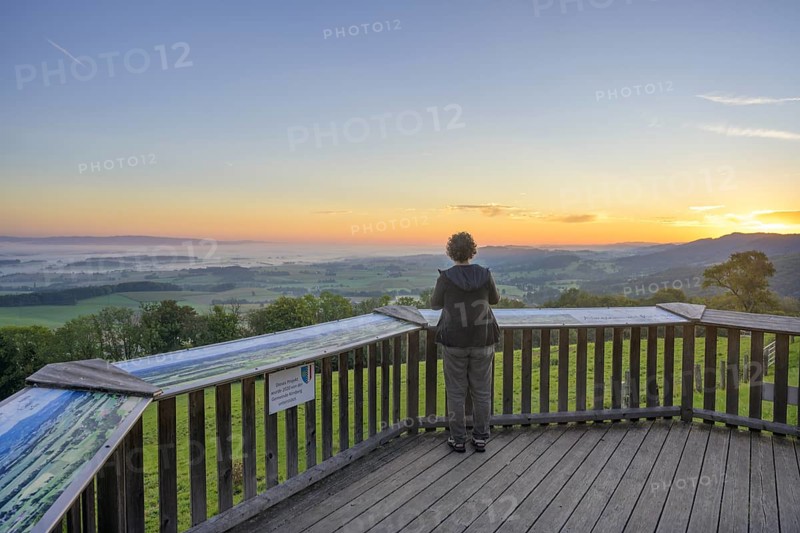 Woman looking at the sunrise from the viewing terrace at Almhaus Hochsteinberg, Kirnberg an der Mank, Lower Austria, Austria