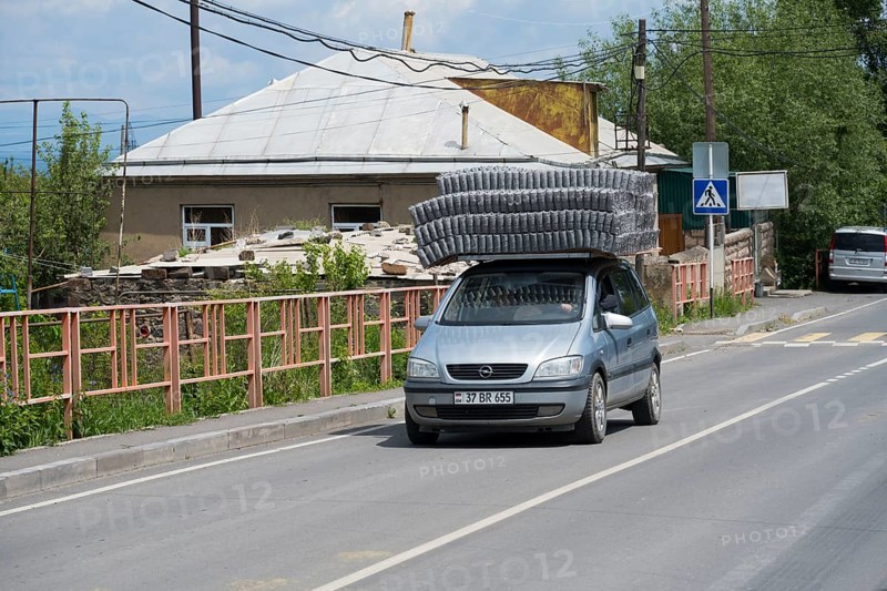 A car carrying goods on its roof, driving along an urban road, Geghhovit, Geghahovit, Verin Gharanlugh, Gegharkunik province, Armenia